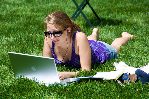 How to Earn Online? Girl using apple laptop in grasses.