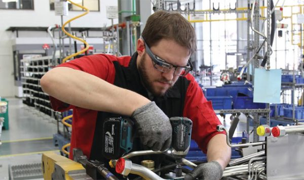 A worker wears a Google Glass Enterprise Edition while assembling machine parts.